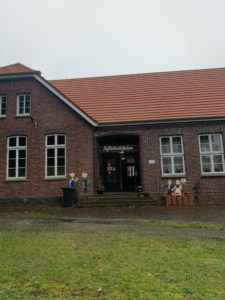 Das Schulgebäude in Bohlenbergerfeld, in dem Emil Lang für einige Jahre unterrichtet und sogar mit seiner Familie gewohnt hat. Links und rechts vom Eingang stehen Figuren von Kindern, die die Besucher zum Schulmuseum einladen, dass sich heute in der alten Schule befindet. 